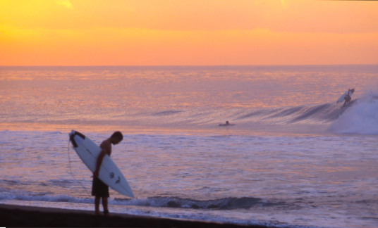 Man contemplating surfing at sunset